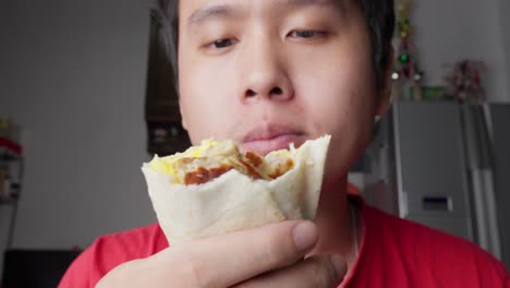 Portrait-Of-Young-Man-Eating-Showing-Delicious-Scrambled-Egg-and-Sausage-Burrito