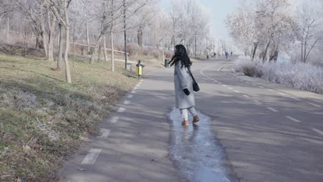 Woman-Sliding-Through-The-Frozen-Puddle-in-The-Road-In-Winter
