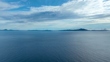 Scene-of-blues,-horizon,-island-background,-ocean,-sky-and-clouds,-aerial