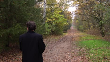 Mann-Im-Schwarzen-Mantel-Geht-Im-Wald-Spazieren-Und-Schaut-Sich-Um,-Rückansicht