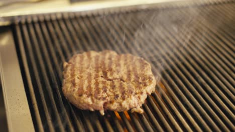 Saftiges-Burger-Patty-Brutzelt-Auf-Dem-Grill,-Dampf-Steigt-Auf,-Nahaufnahme,-Inneneinstellung