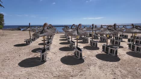 Mallorca-Sandstrand-In-Cala-Bona-Mit-Liegestühlen-Und-Sonnenschirmen-Warten-Auf-Die-Saison-Sonnig-Blau