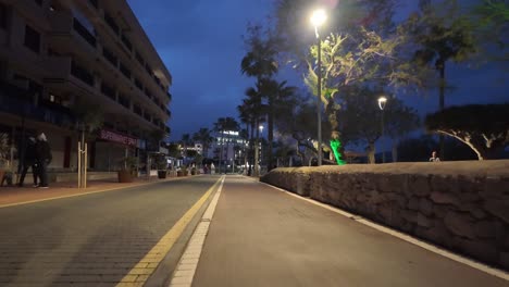 Promenade-well-lit-during-nighttime-and-still-pedestrians-enjoy-in-costal-Cala-Bona-in-Mallorca,-Spain