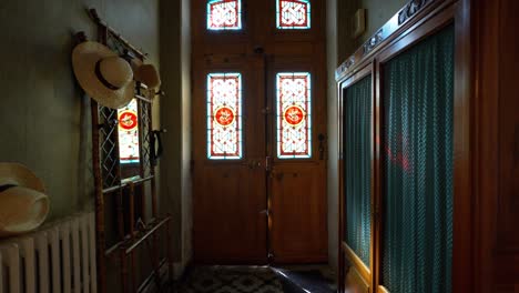 Slow-dolly-shot-of-a-stained-glass-villa-door-with-a-wardrobe-and-hat-stand