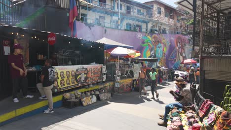 Smoke-rises-from-street-food-vendors-as-locals-walk-along-roads-past-shops-at-Comuna-13,-Medellin