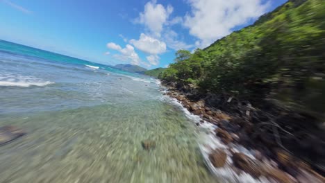 Caribbean-paradise,-FPV-flight-along-the-rocky-jungle-coast-sunny-day