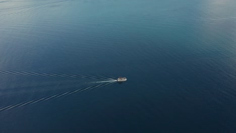 Imágenes-De-Seguimiento-De-Drones-De-Un-Barco-Navegando-En-Un-Lago-De-Gallineta-Nórdica-Rodeado-De-Agua-Azul