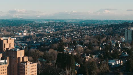 Fly-past-Pacific-Tower-and-over-Beacon-Hill-to-see-a-wide-view-of-Seattle-residential-neighborhoods-sprawling-towards-Mount-Rainier-on-the-horizon