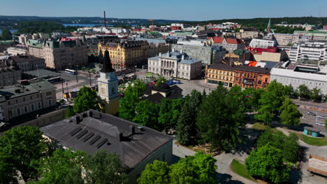 Aerial-view-around-a-chimney,-revealing-the-Keskustori-market-in-Tampere,-summer-day