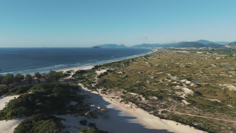 Panoramic-bird's-eye-view-captures-the-entirety-of-Joaquina-Beach-in-Florianopolis,-Santa-Catarina,-Brazil,-showcasing-its-vast-expanse-and-stunning-coastal-beauty
