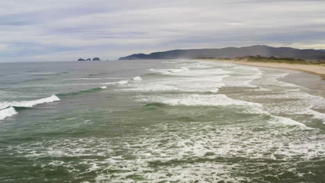 Ocean-waves-break-crashing-and-leaving-trail-of-foam-white-wash-behind-in-water,-Oregon-Coast