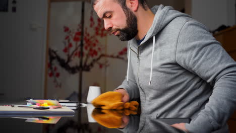 Middle-Eastern-Caucasian-Guy-Wiping-Table-With-Glass-Surface-Before-Starting-To-Work
