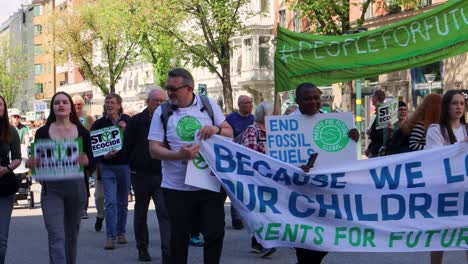 Gente-Marchando-En-Protesta-Ambiental-Con-Pancartas-En-Estocolmo,-Día-Soleado