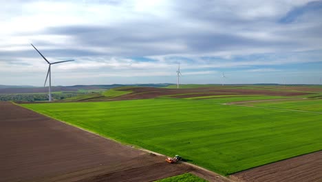 Wind-turbines-and-tractor-working-on-land-at-sunset-in-Ruginoasa-Iasi-Romania