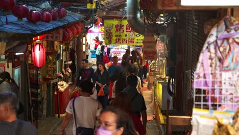 People-wander-through-a-charming-alley-lined-with-food-stalls-and-unique-souvenir-boutiques-in-Jiufen-Old-Street,-popular-tourist-spot-nestled-in-Taiwan's-mountain-town