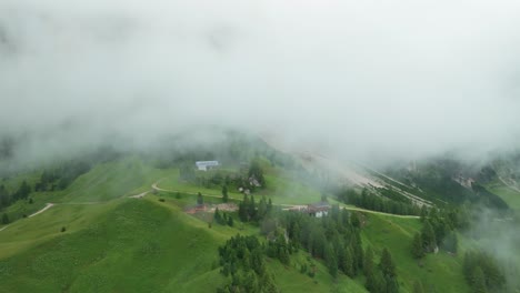 A-drone-flies-close-to-the-clouds-approaching-a-mountain-restaurant-on-the-slopes-near-Val-Gardena-pass,-South-Tyrol,-Italy