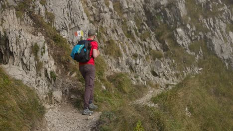 Hiker-Walking-Along-Mountain-Side-Path-In-Lecco-Alps-With-Foggy-Air-In-background