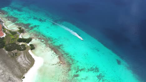 Aerial-top-down-view-of-a-boat-navigating-through-clear-waters-near-a-reef-by-Cayo-de-Agua