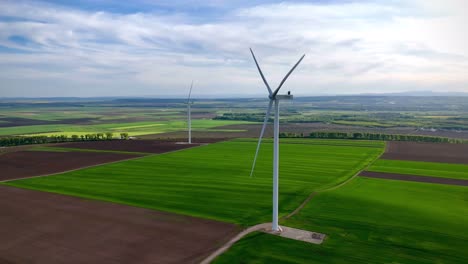 Vista-Aérea-De-Drones-De-La-Turbina-Eólica-En-La-Ciudad-De-Ruginoasa-De-Rumania-En-Un-Día-Soleado-Con-Fondo-De-Hierba-Verde