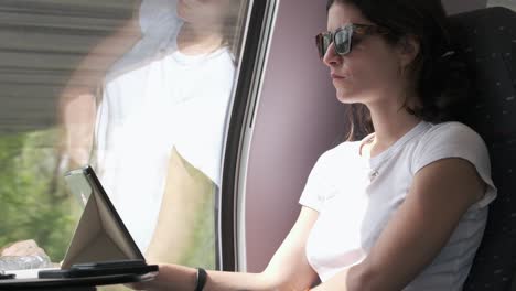 Frau-Mit-Sonnenbrille-Benutzt-Tablet-Auf-Zugfahrt