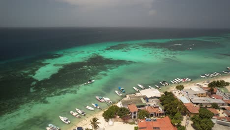 Gran-roque-village-in-los-roques-with-boats-and-turquoise-sea,-aerial-view