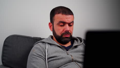 Caucasian-Man-With-A-Beard-Working-On-His-Laptop-Looking-Anxious