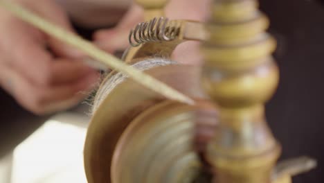 Narrow-focus-artisan-spins-wool-fibre-on-vintage-Nordic-spinning-wheel