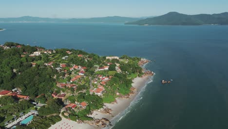 A-panoramic-view-captures-the-left-end-of-Jurerê-Internacional-Beach,-featuring-the-historic-Forte-São-José-da-Ponta-Grossa,-in-Florianopolis