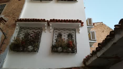 Traditionelle-Hausfassade-Und-Eingangstür-Aus-Chefchaouen,-Marokko,-Mit-üppig-Pflanzengeschmückten-Fenstern-Und-Weiß-Bis-Blau-Gestrichenen-Wänden