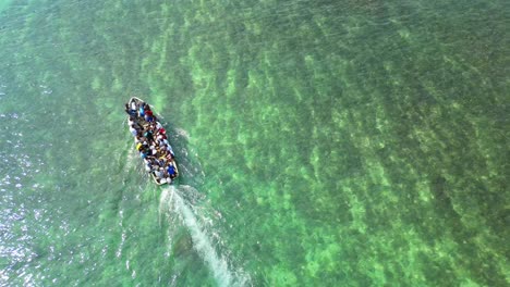 Seen-from-above-a-boat-full-of-people-leaving-the-beach-and-revealing-the-sea-at-Ilheu-das-Rolas-in-São-Tomé,Africa