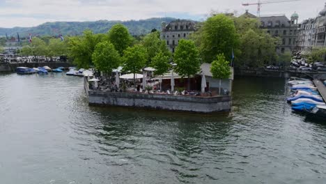 Left-moving-orbit-shot-of-restaurant-in-Zurich-city-on-the-river-front