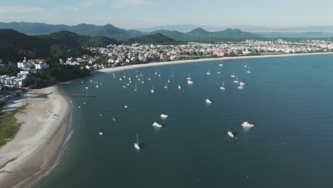 Aerial-view-of-boats-anchored-in-front-of-the-stunning-Jurere-Beach-in-Florianopolis,-on-a-beautiful-sunny-morning