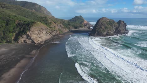 People-At-Black-Sand-Piha-Beach-On-Sunny-Morning-Near-Tasman-Lookout-And-Taitomo-Island-In-New-Zealand