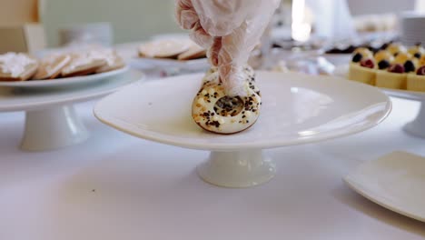 Hand-Legt-Glasierten-Donut-Auf-Dessert-Buffet-Tisch,-Schließen-Auszug