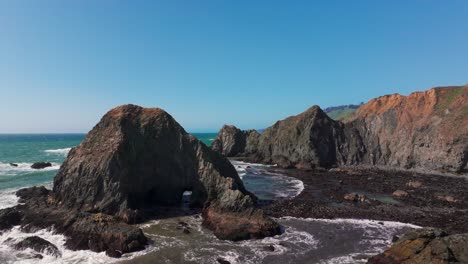 Cinematic-drone-shot-flying-low-through-sharp-rocks-off-the-coast-of-California