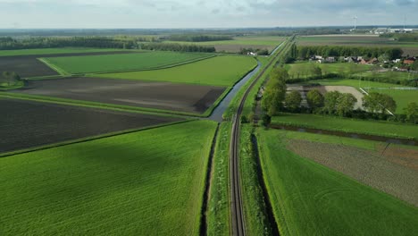 Following-a-train-track-in-a-Dutch-polder-landscape-with-a-drone