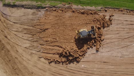 Top-down-of-a-bull-dozer-flattening-out-earth-on-a-heavily-worked-construction-site