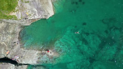 Gente-Nadando-En-Aguas-Turquesas-A-Lo-Largo-De-La-Costa-Rocosa-De-Cornualles-Desde-Un-Dron-Aéreo-Arriba