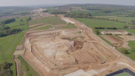 Drone-vista-of-a-large-scale-construction-site-within-a-rural-setting,-diggers,-loaders-and-bulldozers
