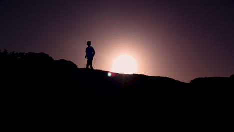 Silhouette-Eines-Kleinen-Jungen,-Der-Von-Rechts-Nach-Links-Rennt,-Während-Die-Sonne-Aufgeht