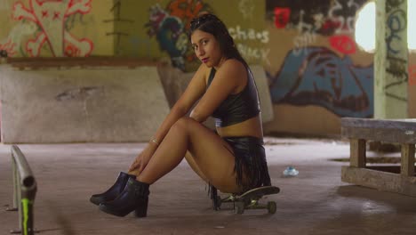 With-a-skateboard-in-hand,-a-girl-in-a-mini-skirt-explores-an-indoor-skate-park