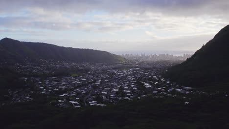Einspielung-Einer-Kleinen-Wohninselstadt-Eingebettet-Zwischen-Zwei-Mit-Regenwald-Bedeckten-Bergen-Mit-Blick-Auf-Die-Stadt-Am-Horizont-In-Der-Schlucht-Auf-Der-Insel-Oahu,-Hawaii,-Am-Späten-Nachmittag