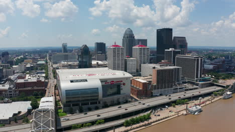 Stationary-aerial-shot-of-downtown-city-during-the-day-with-cars-driving-on-the-freeway-down-below