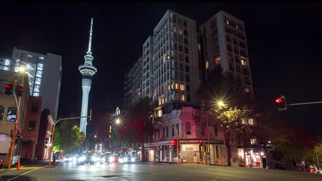 Concurrida-Intersección-En-Auckland,-Nueva-Zelanda,-Torre-Del-Cielo-En-El-Fondo,-Timelapse-Nocturno