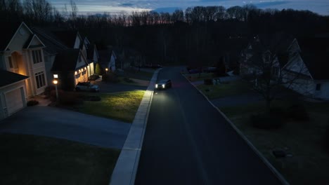 Car-with-headlights-on-parked-in-large-neighborhood-in-USA-at-night