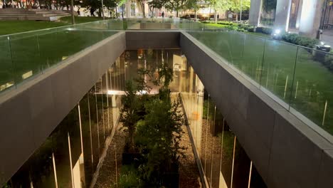 Nighttime-view-of-a-serene-indoor-garden-at-Nueva-Las-Condes,-visible-through-glass-bridges