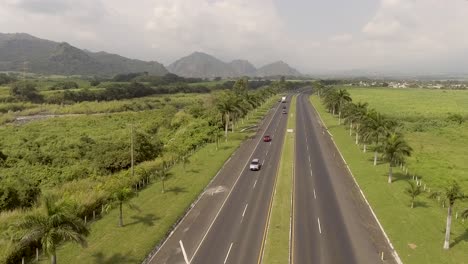 Dolly-Aéreo-En-Autos-Rodados-Circulando-Por-La-Autopista-CA2-En-Guatemala,-El-Volcán-De-Pacaya-En-Segundo-Plano.