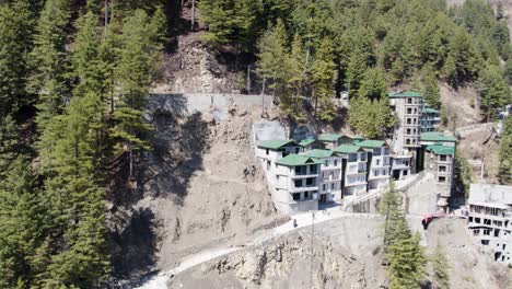 modern-buildings-constructed-on-a-steep-mountain-slope-surrounded-by-dense-pine-forests
