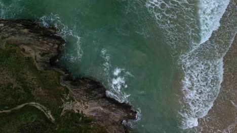 Luftaufnahme-Von-Oben-Nach-Unten-über-Einen-Strand-In-Cornwall-Mit-Meereswellen,-Die-Entlang-Der-Felsigen-Küste-Brechen,-Großbritannien