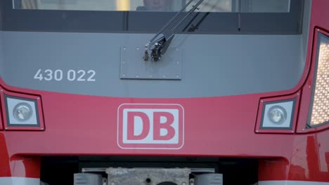 Close-up-shot-of-a-Deutsche-Bahn-train-highlighting-the-DB-logo-and-front-lights,-panning-camera-movement
